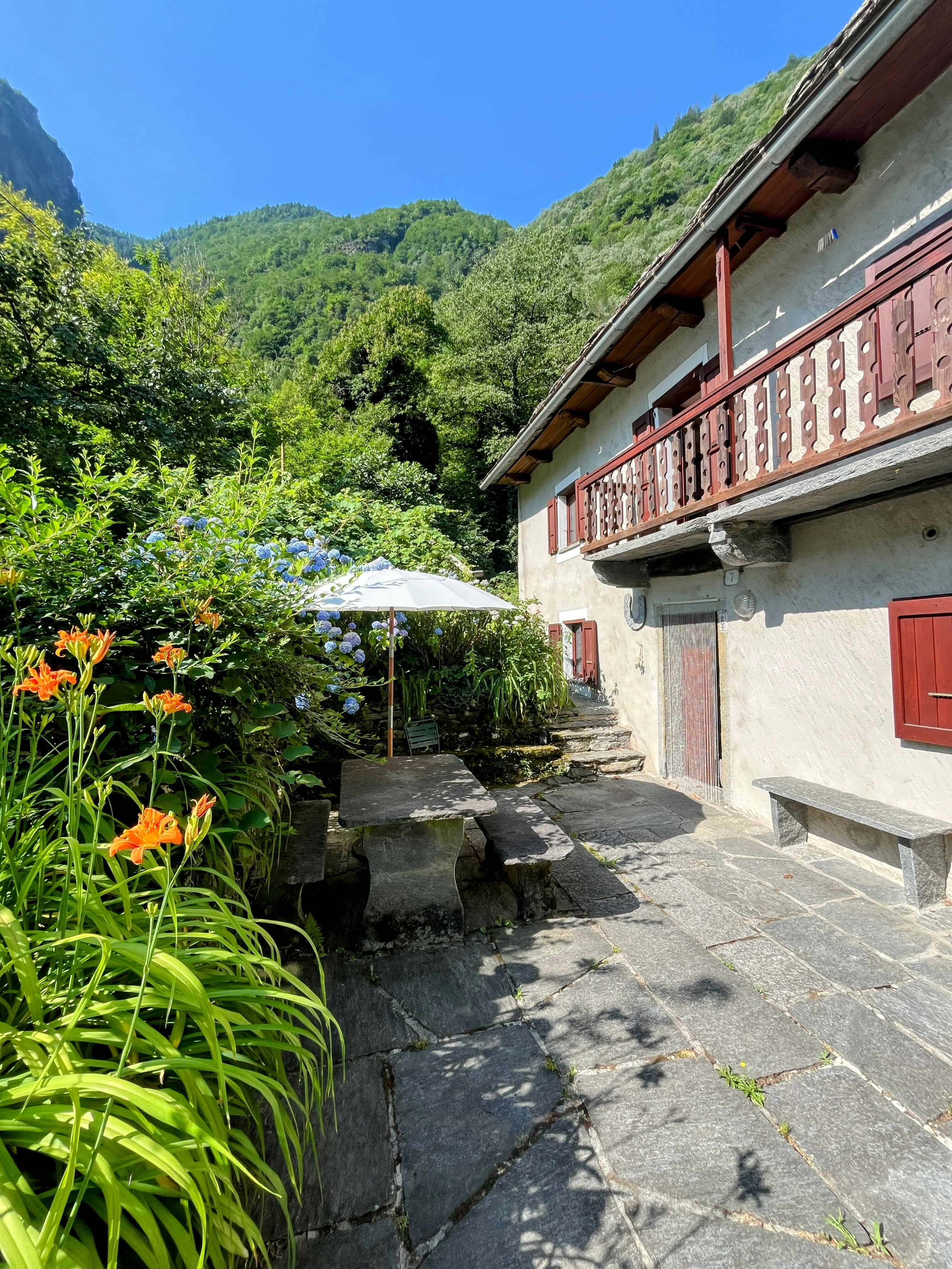 Casa Isolina Aussenansicht mit Loggia, Blumen und Bergen